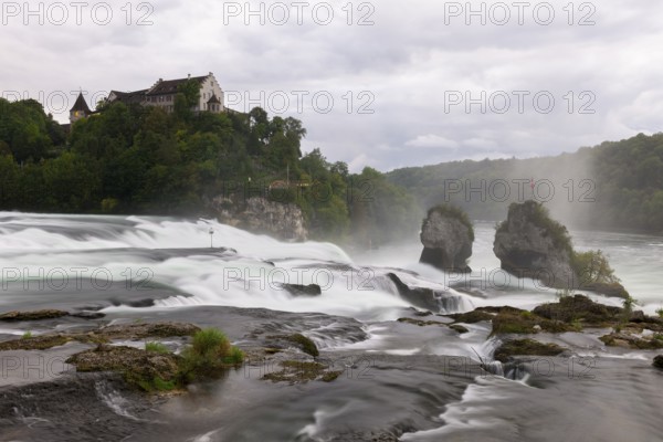 Dramatic waterfall flows past rocks to a castle, Schloss Laufen, Rhine Falls, Canton Schaffhausen,