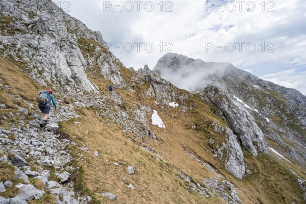 Mountaineer on a narrow hiking trail, ascent to the Maukspitze, clouds moving around the mountains,