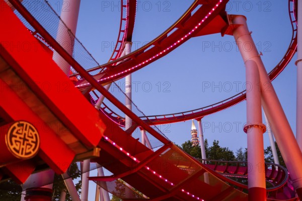 Red-lit roller coaster at dusk, Tivoli Amusement and Recreation Park, Copenhagen, Denmark, Europe