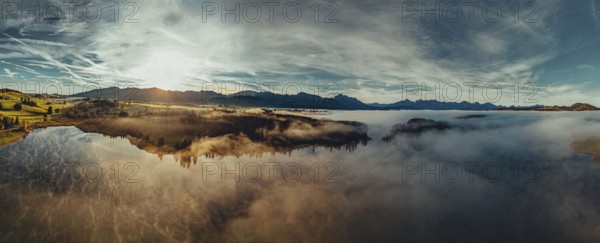 Autumn sunrise in the foothills of the Alps with fog at Illasbergsee and Forggensee near Halblech