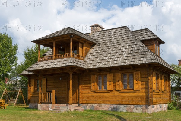 Traditional, light brown wooden house with veranda surrounded by sunshine, Bialowieza, Bialowieza,