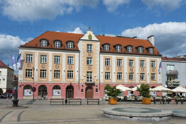 Colourful historical building on a sunny day with benches and bicycles in the foreground, bank