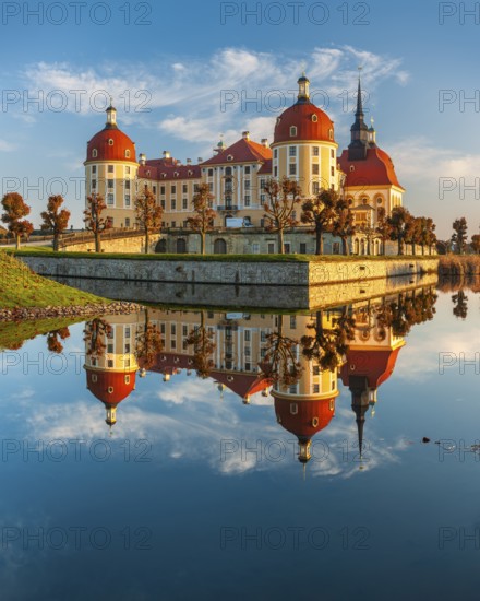 Moritzburg Castle in autumn under a blue sky, reflection in the castle pond, hunting lodge of