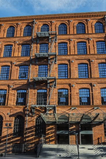 Facade of a brick building with rows of windows and shadows from a staircase, Manufaktura, Lódz,