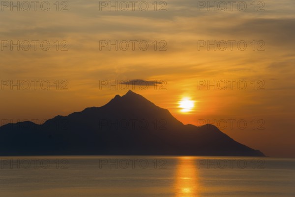 Sunrise behind a mountain with golden reflections on the sea, view of Mount Athos, Orthodox