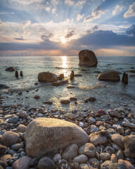 Sunrise on the shore of the Baltic Sea, boulders and old groynes in the water, Jasmund National