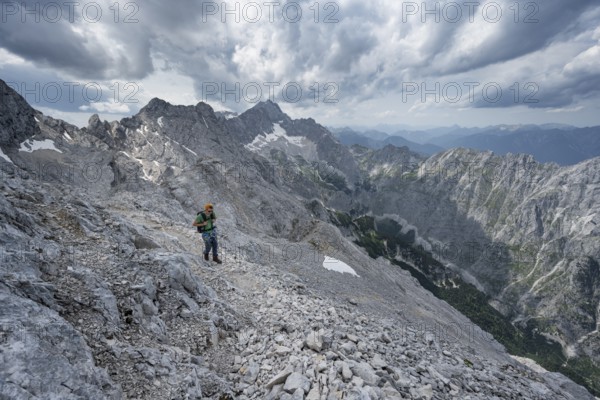 Mountaineer with helmet on a narrow rocky path, crossing the Jubiläumsgrat, view of Zugspitze and