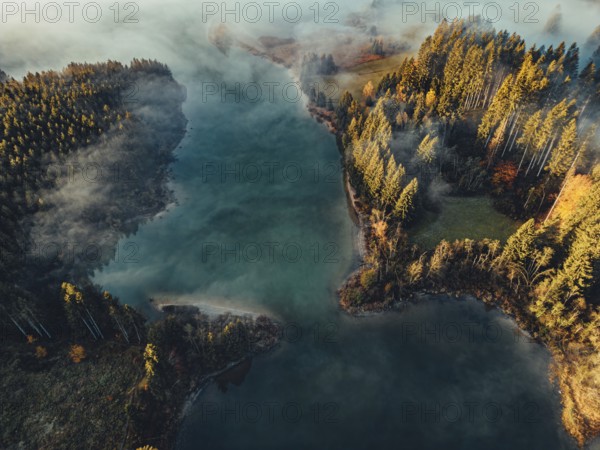 Autumn sunrise in the foothills of the Alps with fog at Illasbergsee and Forggensee near Halblech