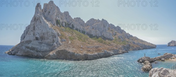 A beautiful island with a rocky coastline and a blue sea. The island is surrounded by a rocky cliff