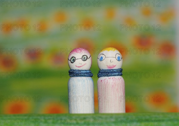 Two small funny wooden cones in front of a painted background, North Rhine-Westphalia, Germany,
