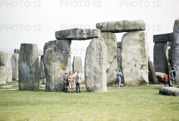 People exploring the standing stones at the Neolithic site of Stonehenge, Wiltshire, England, UK