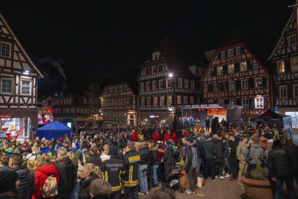 Large crowd gathers at night for a celebration in front of half-timbered houses, carnival, Calw,