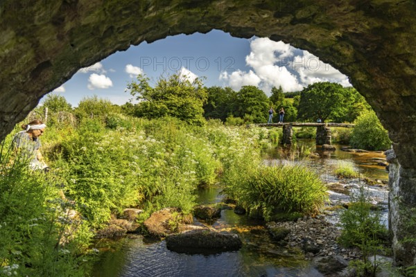 Tourists on the medieval stone slab bridge Clapper Bridge in Postbridge, Dartmoor, Devon, England,