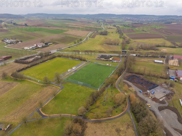 Green sports field surrounded by fields and scattered trees in a rural setting, Großbottwar,