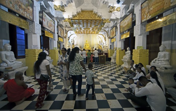 Sri Lankan pilgrims at the golden Buddha in the Buddhist Temple of the Tooth or Sri Dalada