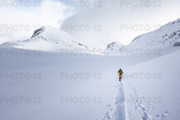Lone ski tourer in snowy mountain landscape, ascent to the Wildhorn, cloudy mood, high tour,