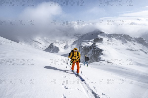 Ski tourers climbing the Wildhorn, Snowy mountain landscape and fog, Bernese Alps, Bernese