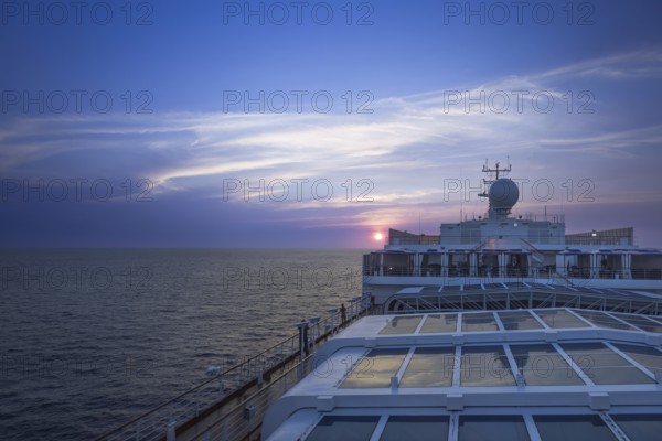 Cruise docked near scenic ocean beach landscape on a cruise vacation at sunset.