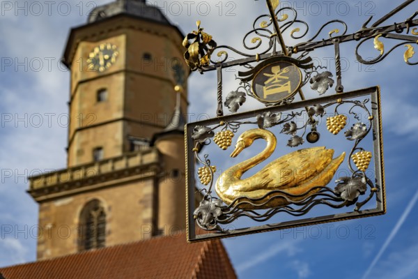 Golden sign Hotel Zur Schwane and the church tower of St Bartholomew in Volkach, Lower Franconia,