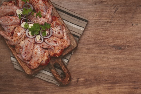 Chicken wings, marinated and laid out on a wooden platter, ready for cooking, grilling or baking,