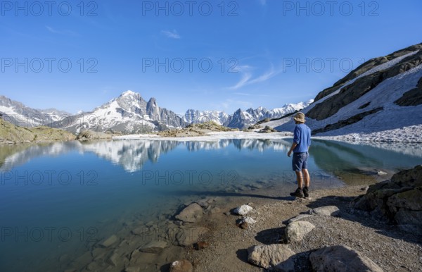 Mountaineer in front of mountain landscape with mountain lake, tourist at Lac Blanc with water