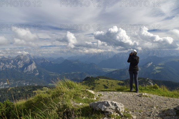 Hiker enjoying the view from the summit of the Sonntagshorn to the horse-rider Alm and Loferer