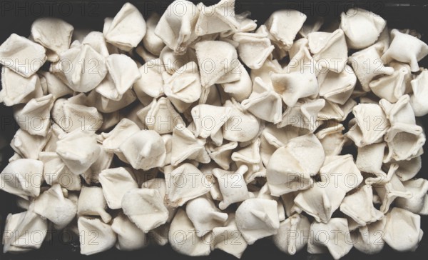 Traditional Turkish dumplings, raw, in a black container, top view, no people