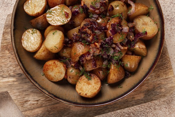 Golden roasted potatoes are served in a rustic bowl, topped with sweet caramelized onions and