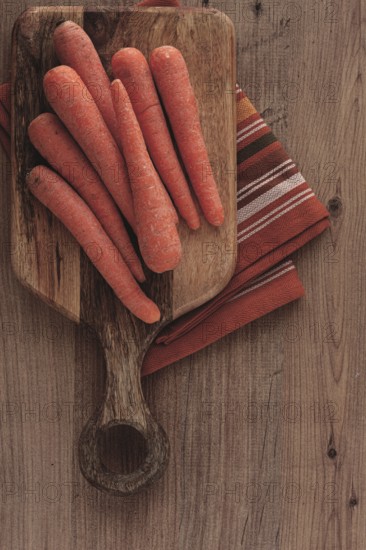 Fresh carrots on a chopping board, wooden table, raw carrots, no people