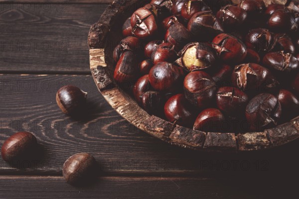 Roasted chestnuts, in a wooden plate, top view, homemade, no people