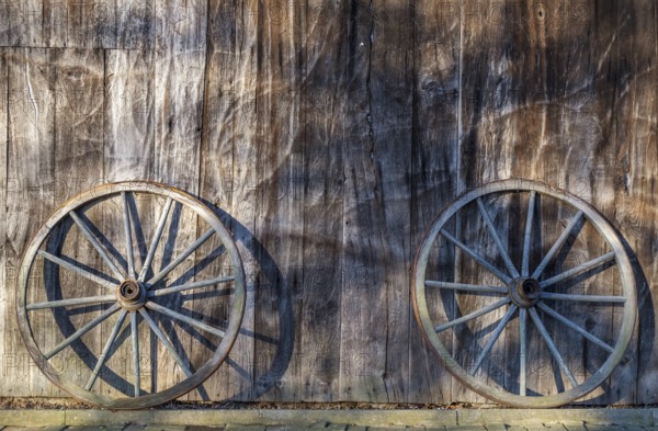 Two wagon wheels leaning against a barn wall, Düstermühle, Legden, district of Wehr, Münsterland,