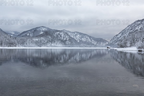 Snow covered boat shelter on Lake Almsee which is partly frozen and snow covered. Snow on the