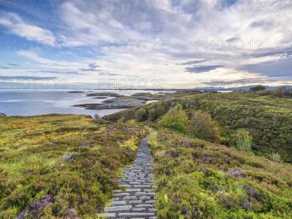 Hiking trail with a view of the sea along the Atlantic Road, blue sky with clouds,