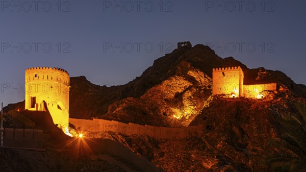 Illuminated city wall with watchtowers at dawn at the Sultan's Palace, Muscat, Arabian Peninsula,