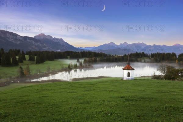 Idyllic mountain landscape with chapel and lake in the evening light, peaceful atmosphere, crescent