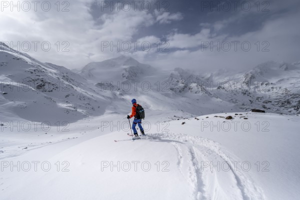 Ski tourers on the descent, behind the summit of Monte Cevedale, snow-covered mountain landscape,