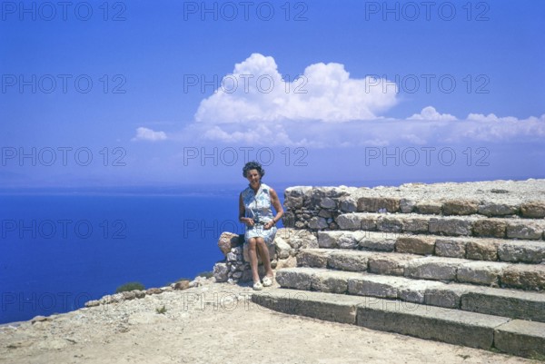 Woman tourist sitting on stone wall at Roman ruins of Vouni Palace, Lefke, Northern Cyprus, Europe