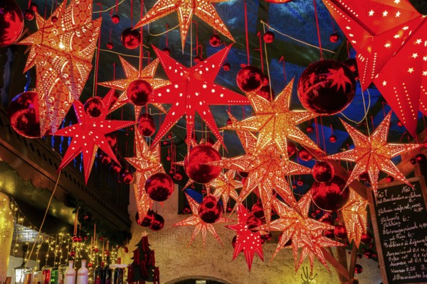 Decoration with stars and baubles above mulled wine stand in side passage at Christmas market, Bad