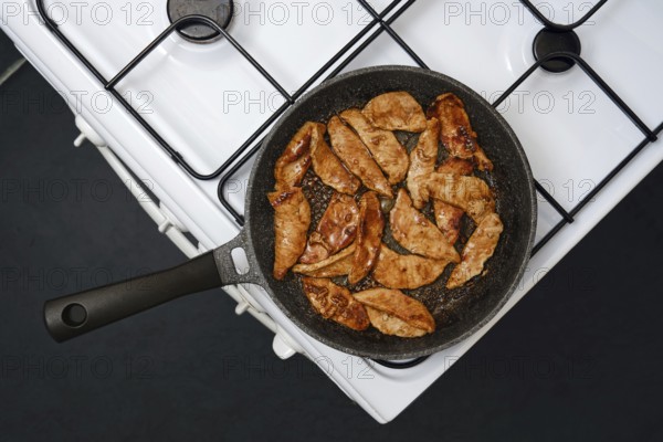 Juicy marinated pork strips sizzle in a frying pan, showcasing their golden brown color while being