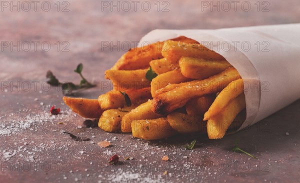 Fried French fries, in a paper bag, on an abstract background, no people, rustic