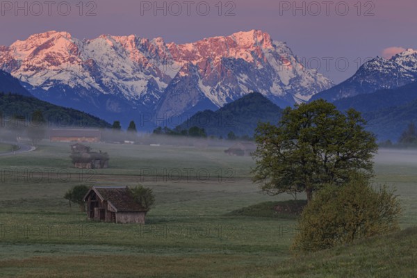 Hut and meadow in front of mountain range, morning light, spring, snowy, view of Zugspitze,