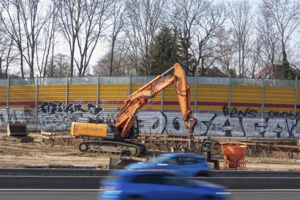 Excavator working on a construction site next to a graffiti-covered wall, Magdeburg, Saxony-Anhalt,