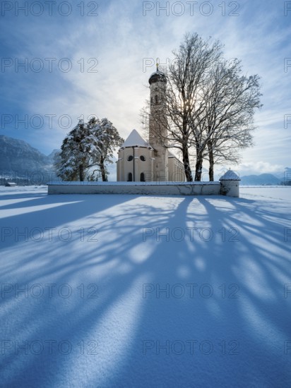 The pilgrimage church of St Coloman in a snow-covered landscape in winter backlit, Schwangau,