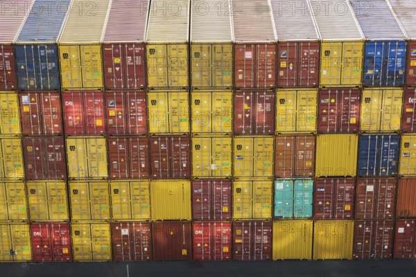 High angle view of stacked yellow and reddish brown MSC, TEX and CAI metal box shipping containers