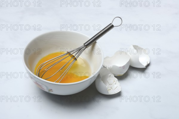 Whipped egg in shell with whisk, egg shells