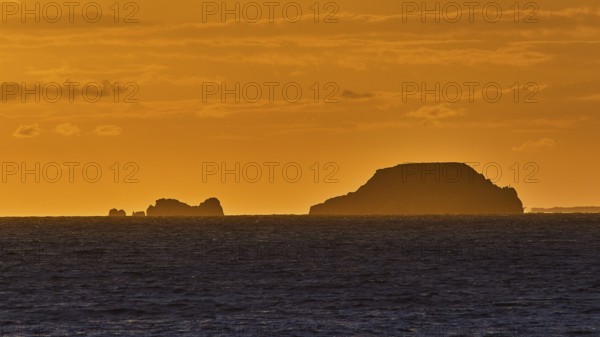 Silhouette of islands in the sea during an orange-coloured dusk with a clear sky, sunset, Kassos,