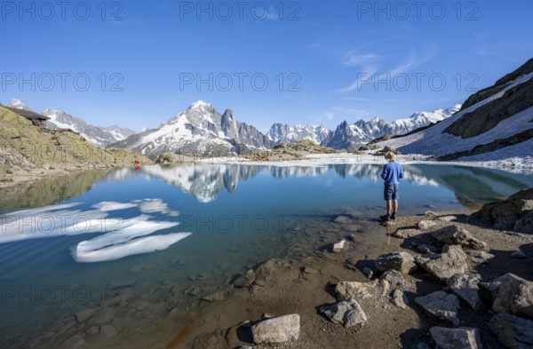 Mountaineer in front of mountain landscape with mountain lake, tourist at Lac Blanc with water