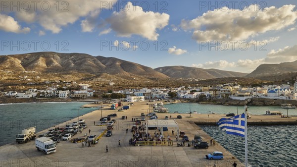 Coastal view of a harbour with a small village and mountains in the background under a blue sky
