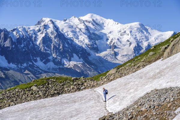 Mountaineer crossing a snowfield, view of spectacular glaciated peaks of Mont Blanc, Mont Blanc