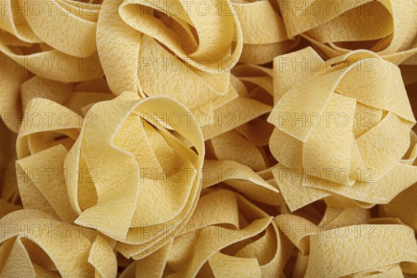 Raw pappardelle pasta, pasta nests, in a paper box, top view, no people